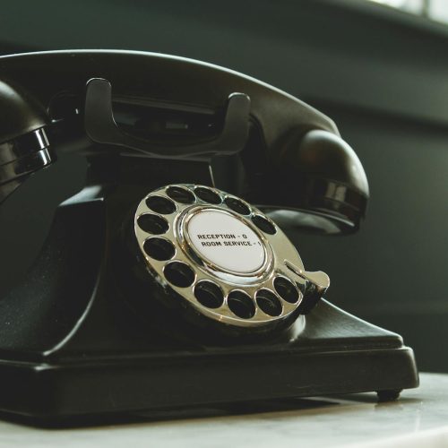Classic black rotary phone on hotel reception desk, evoking nostalgia and vintage charm.